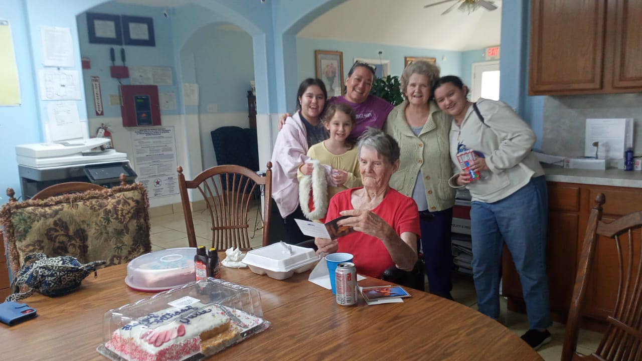 A resident celebrating a birthday surrounded by three generations of visiting family